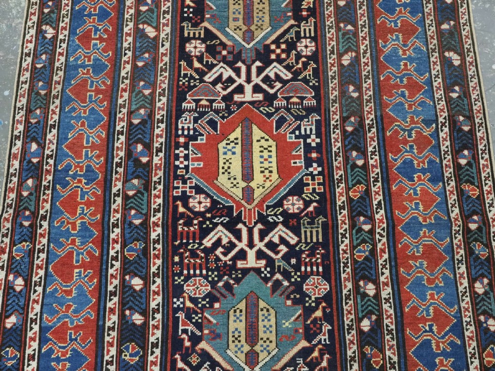 An antique late nineteenth-century Caucasian Kuba runner featuring geometric medallions and stylised animal motifs in navy blue, red, and cream wool. View III