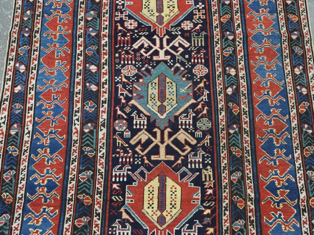 An antique late nineteenth-century Caucasian Kuba runner featuring geometric medallions and stylised animal motifs in navy blue, red, and cream wool. View IV