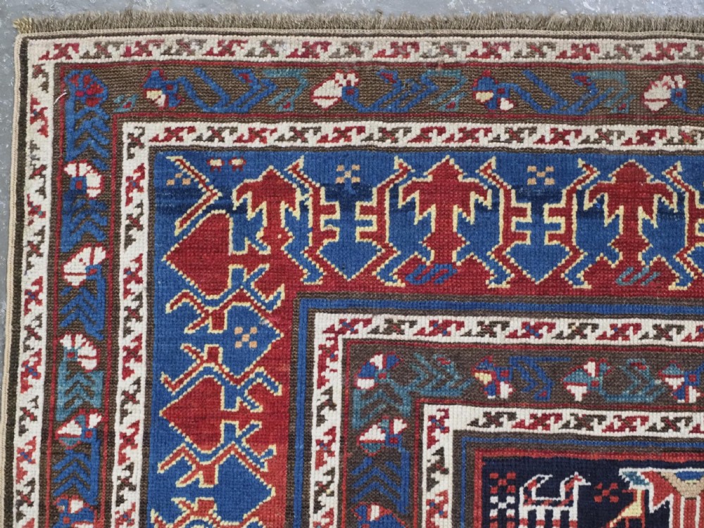An antique late nineteenth-century Caucasian Kuba runner featuring geometric medallions and stylised animal motifs in navy blue, red, and cream wool. View VI