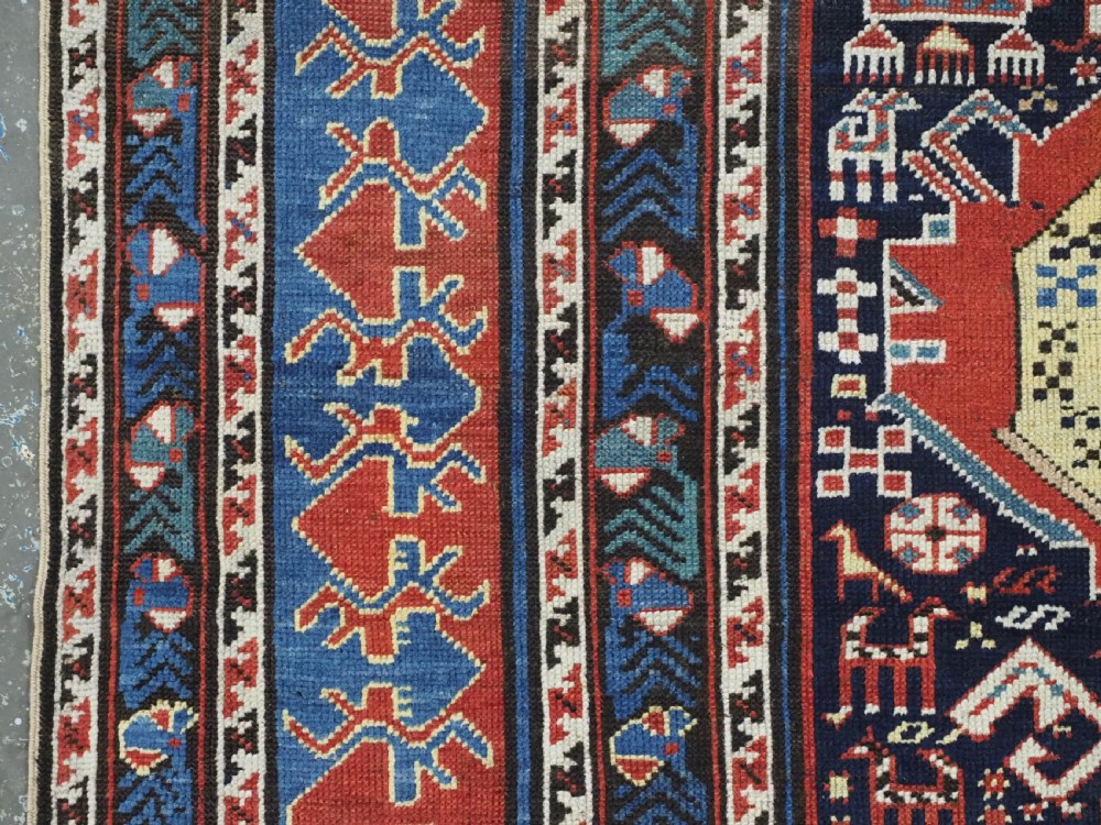 An antique late nineteenth-century Caucasian Kuba runner featuring geometric medallions and stylised animal motifs in navy blue, red, and cream wool. View VII