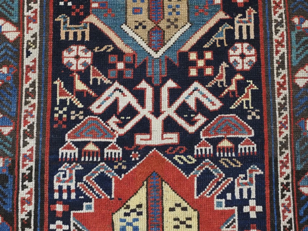 An antique late nineteenth-century Caucasian Kuba runner featuring geometric medallions and stylised animal motifs in navy blue, red, and cream wool. View IX