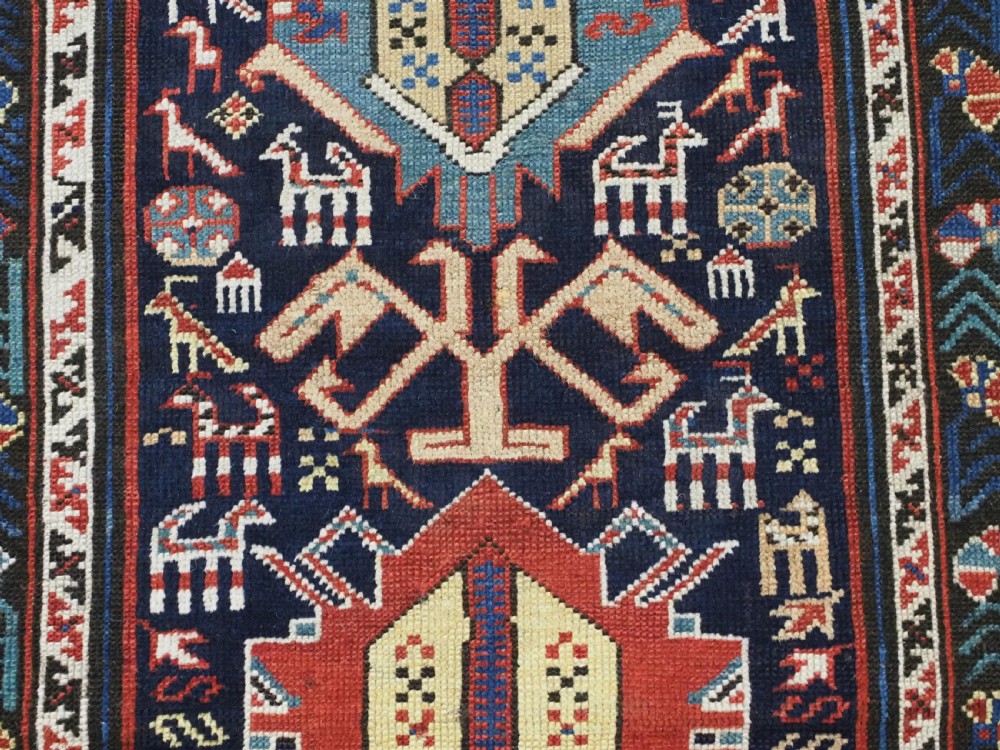 An antique late nineteenth-century Caucasian Kuba runner featuring geometric medallions and stylised animal motifs in navy blue, red, and cream wool. View XI