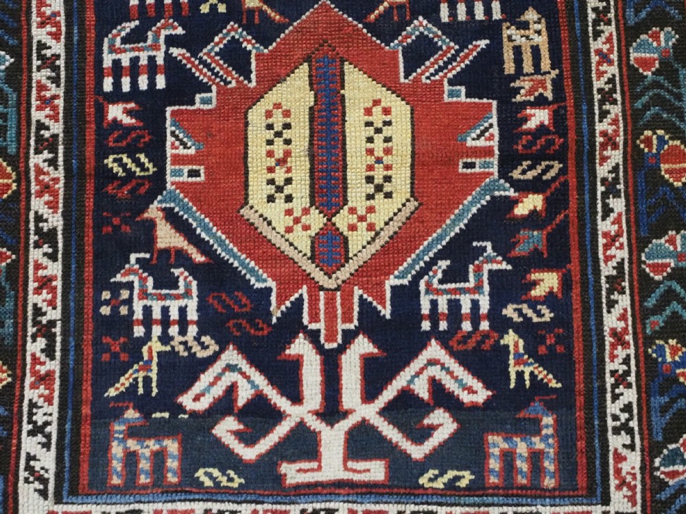 An antique late nineteenth-century Caucasian Kuba runner featuring geometric medallions and stylised animal motifs in navy blue, red, and cream wool. View XII