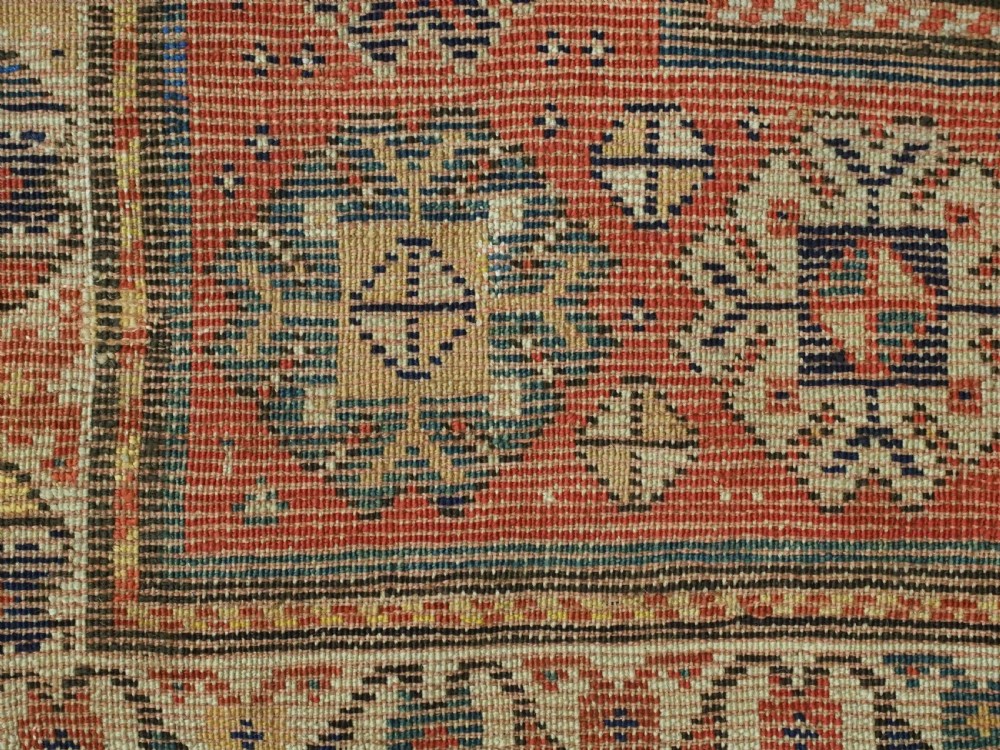 An antique hand-knotted Caucasian runner rug featuring repeated boteh motifs on a dark blue central field framed by red geometric borders. View XII