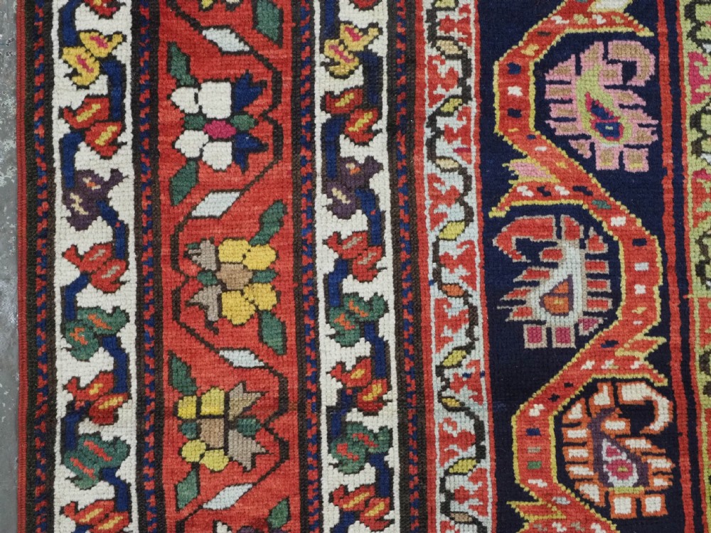 An antique Caucasian Karabagh runner rug featuring vertical polychrome stripes filled with repeating boteh motifs framed by multiple floral borders. View VI
