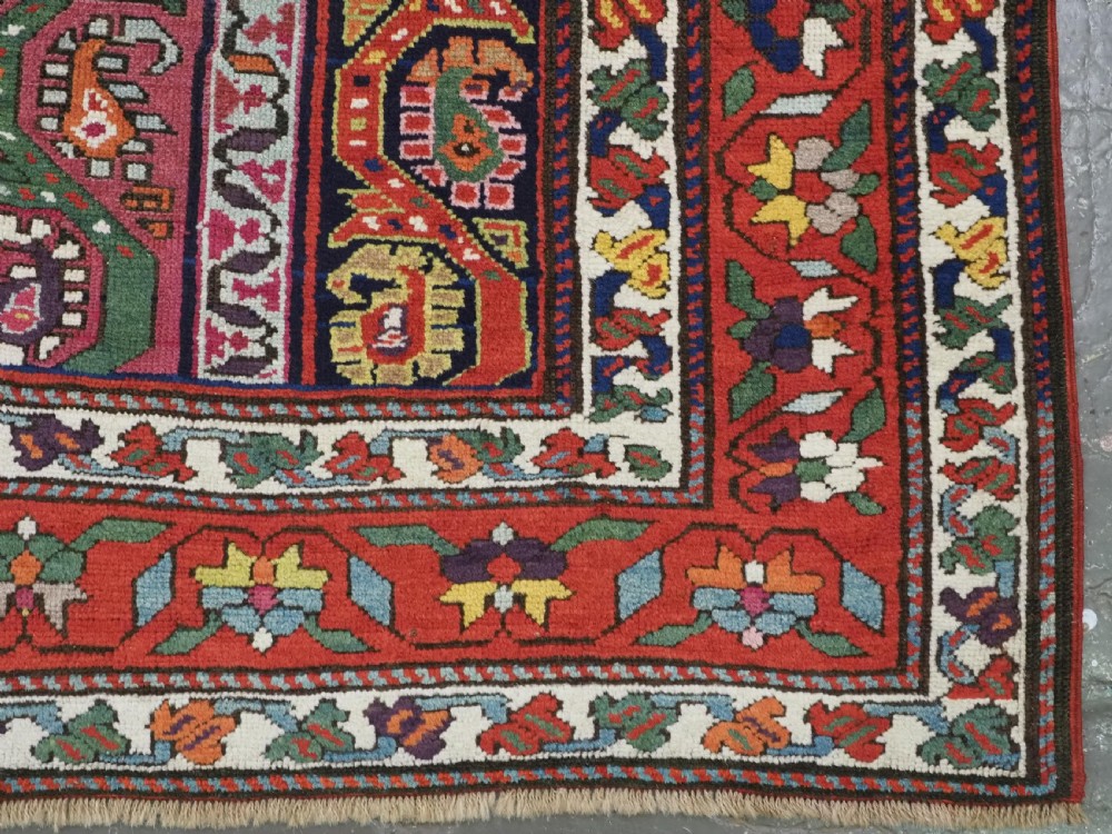 An antique Caucasian Karabagh runner rug featuring vertical polychrome stripes filled with repeating boteh motifs framed by multiple floral borders. View X