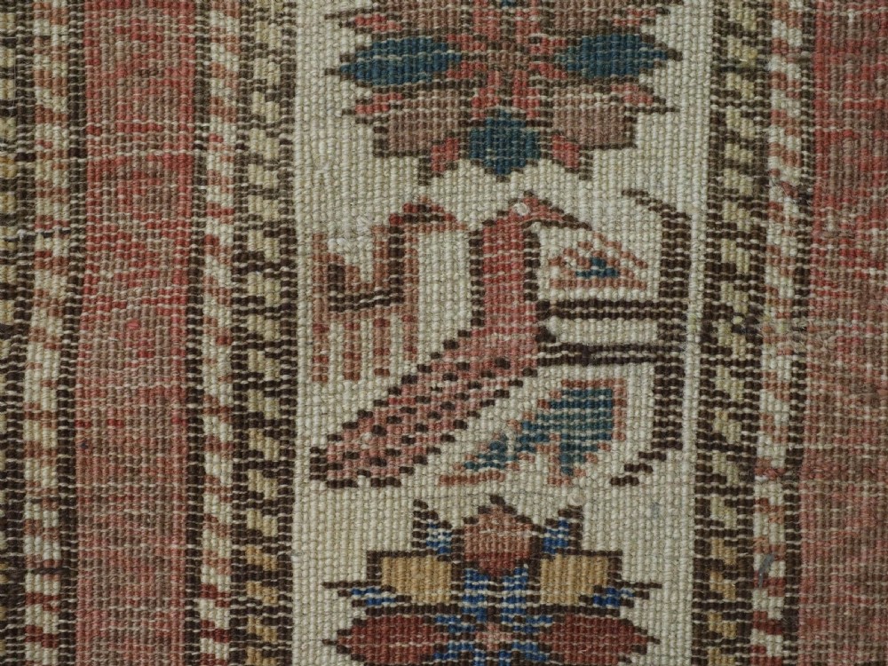 A hand-knotted antique Caucasian wool rug featuring geometric Lesghi star medallions on a dark central field enclosed by an ivory border decorated with stylised bird motifs. View XI