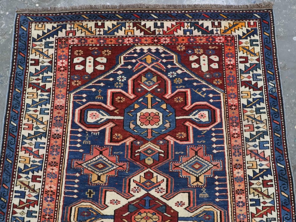 A hand-knotted antique Caucasian rug featuring three lobed medallions on a navy blue field surrounded by intricate geometric borders. View III