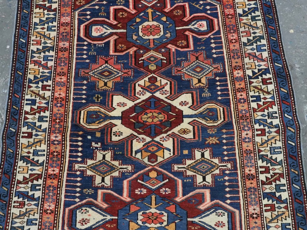 A hand-knotted antique Caucasian rug featuring three lobed medallions on a navy blue field surrounded by intricate geometric borders. View V