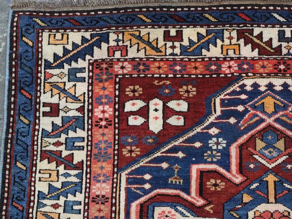 A hand-knotted antique Caucasian rug featuring three lobed medallions on a navy blue field surrounded by intricate geometric borders. View VI