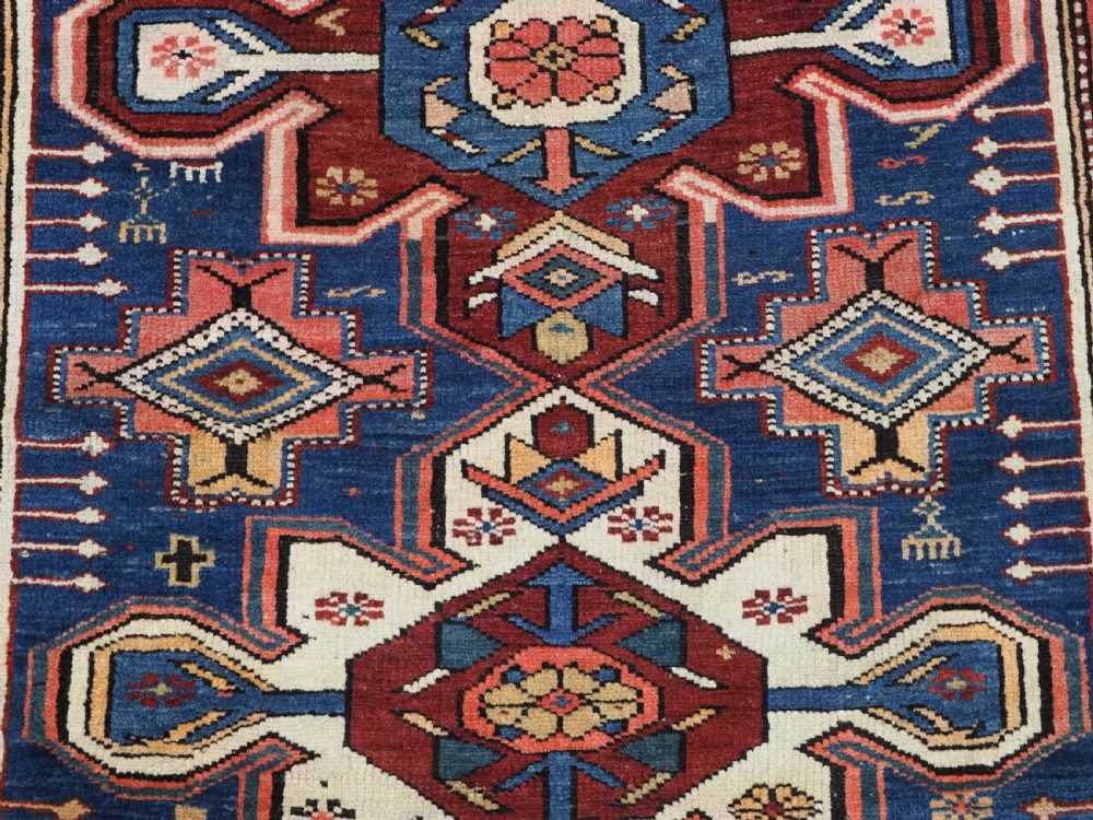 A hand-knotted antique Caucasian rug featuring three lobed medallions on a navy blue field surrounded by intricate geometric borders. View IX