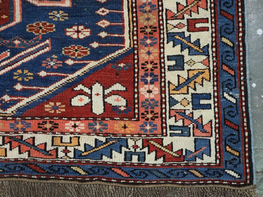 A hand-knotted antique Caucasian rug featuring three lobed medallions on a navy blue field surrounded by intricate geometric borders. View XIII