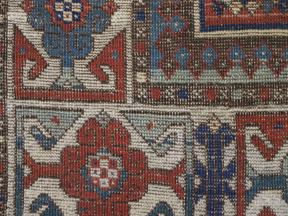 An antique hand-knotted Caucasian wool rug featuring three primary geometric medallions on a terracotta field with navy and cream patterned borders. View XII