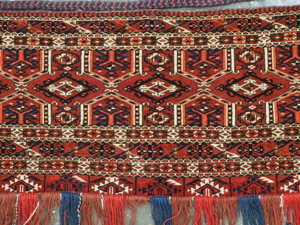 Horizontal handwoven Turkmen wool torba bag featuring deep red and indigo geometric kedjebe motifs with long woollen fringe along the bottom edge. View II