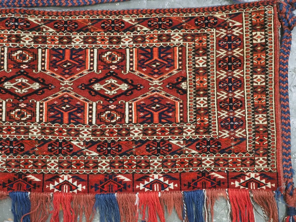 Horizontal handwoven Turkmen wool torba bag featuring deep red and indigo geometric kedjebe motifs with long woollen fringe along the bottom edge. View IV