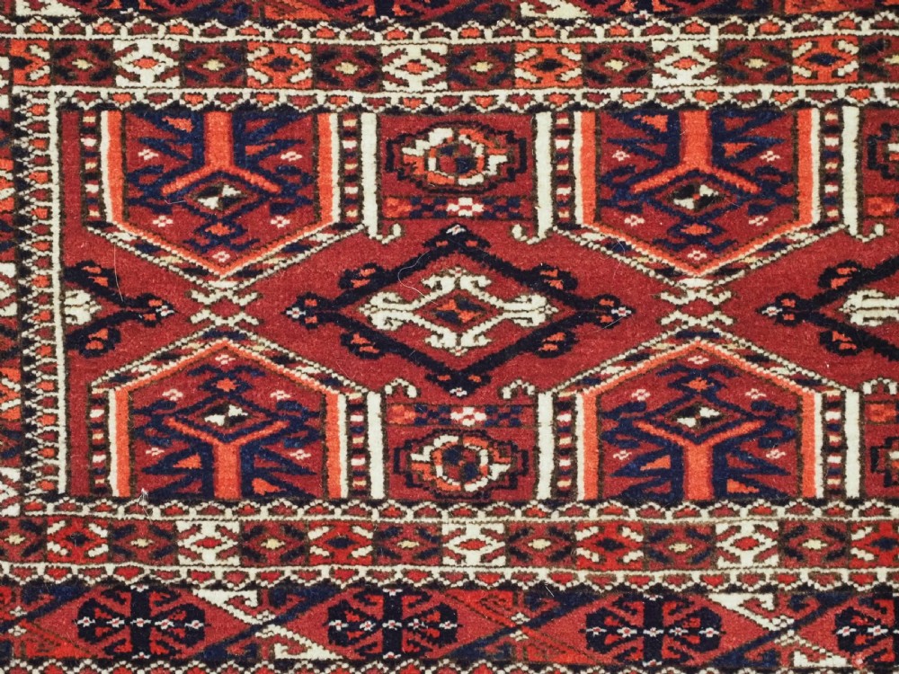Horizontal handwoven Turkmen wool torba bag featuring deep red and indigo geometric kedjebe motifs with long woollen fringe along the bottom edge. View VI