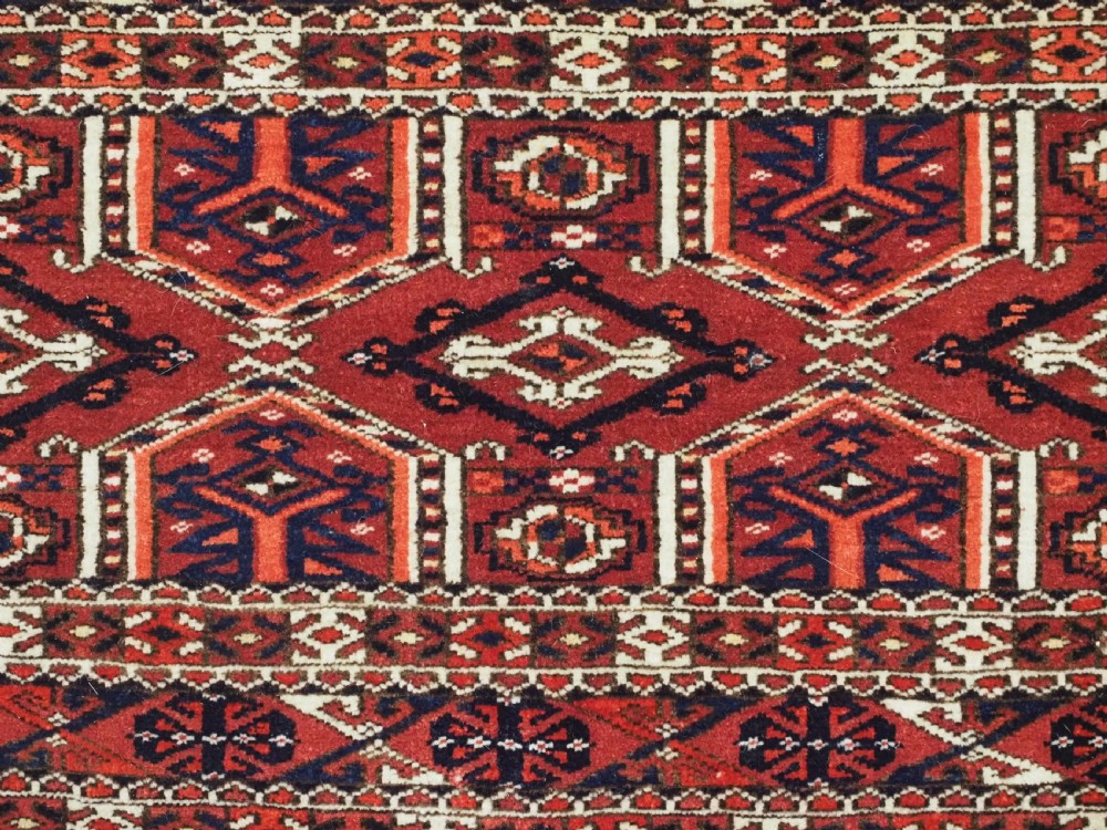 Horizontal handwoven Turkmen wool torba bag featuring deep red and indigo geometric kedjebe motifs with long woollen fringe along the bottom edge. View VII
