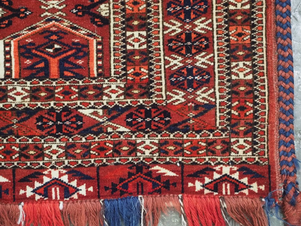 Horizontal handwoven Turkmen wool torba bag featuring deep red and indigo geometric kedjebe motifs with long woollen fringe along the bottom edge. View IX