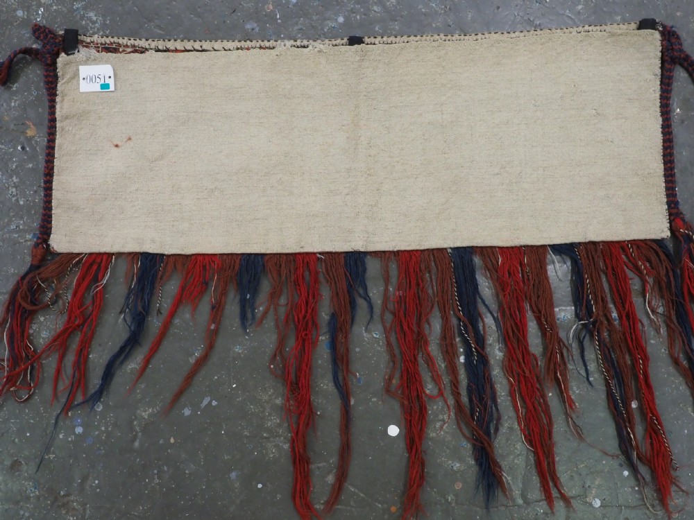 Horizontal handwoven Turkmen wool torba bag featuring deep red and indigo geometric kedjebe motifs with long woollen fringe along the bottom edge. View X