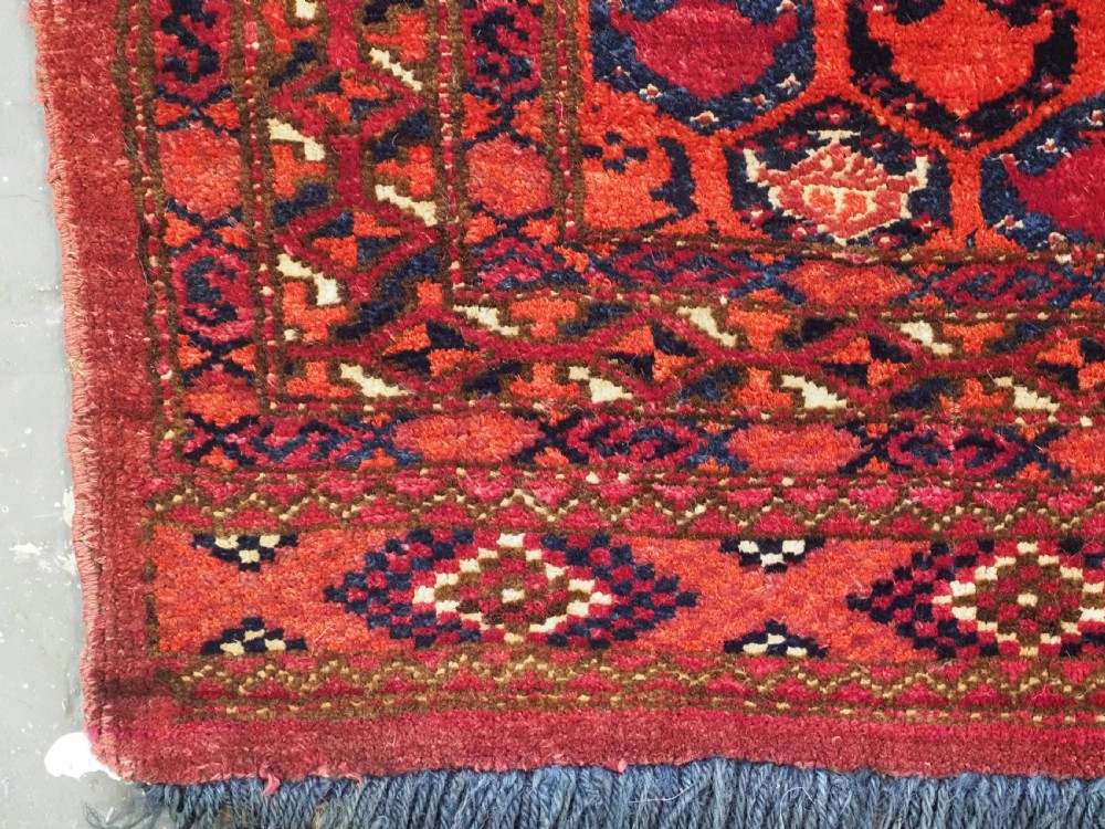 A horizontal rectangular hand-knotted Turkmen torba with repeating red and blue Shemle guls and long wool fringe along the lower border. View VI