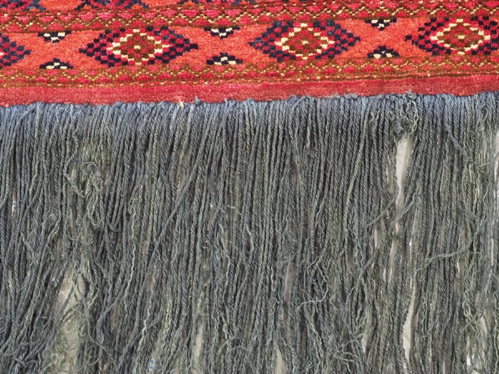 A horizontal rectangular hand-knotted Turkmen torba with repeating red and blue Shemle guls and long wool fringe along the lower border. View X