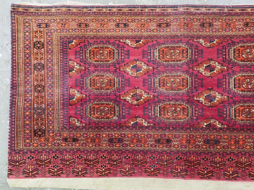 A rectangular hand-knotted crimson red Turkmen chuval featuring nine central octagonal Salor guls framed by ornate geometric borders and a decorative lower elem panel. View II