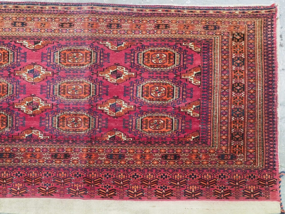 A rectangular hand-knotted crimson red Turkmen chuval featuring nine central octagonal Salor guls framed by ornate geometric borders and a decorative lower elem panel. View III