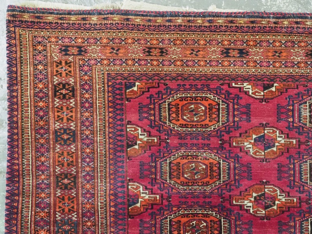 A rectangular hand-knotted crimson red Turkmen chuval featuring nine central octagonal Salor guls framed by ornate geometric borders and a decorative lower elem panel. View IV