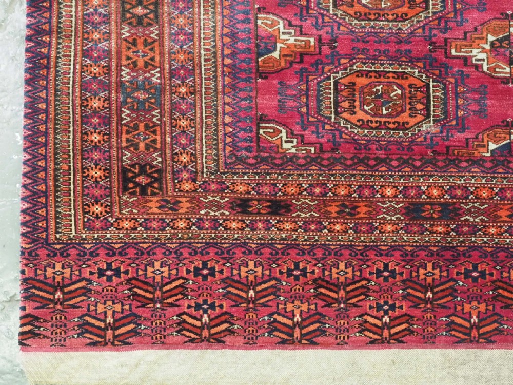 A rectangular hand-knotted crimson red Turkmen chuval featuring nine central octagonal Salor guls framed by ornate geometric borders and a decorative lower elem panel. View V