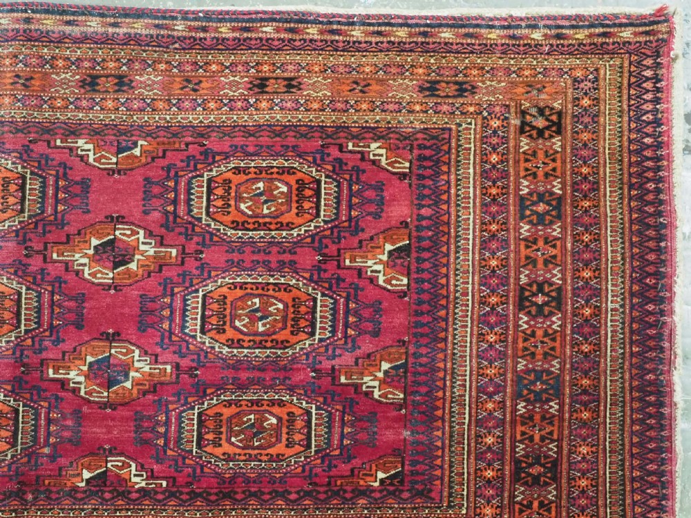 A rectangular hand-knotted crimson red Turkmen chuval featuring nine central octagonal Salor guls framed by ornate geometric borders and a decorative lower elem panel. View VII