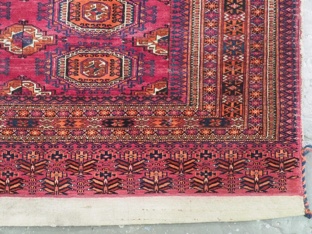 A rectangular hand-knotted crimson red Turkmen chuval featuring nine central octagonal Salor guls framed by ornate geometric borders and a decorative lower elem panel. View VIII