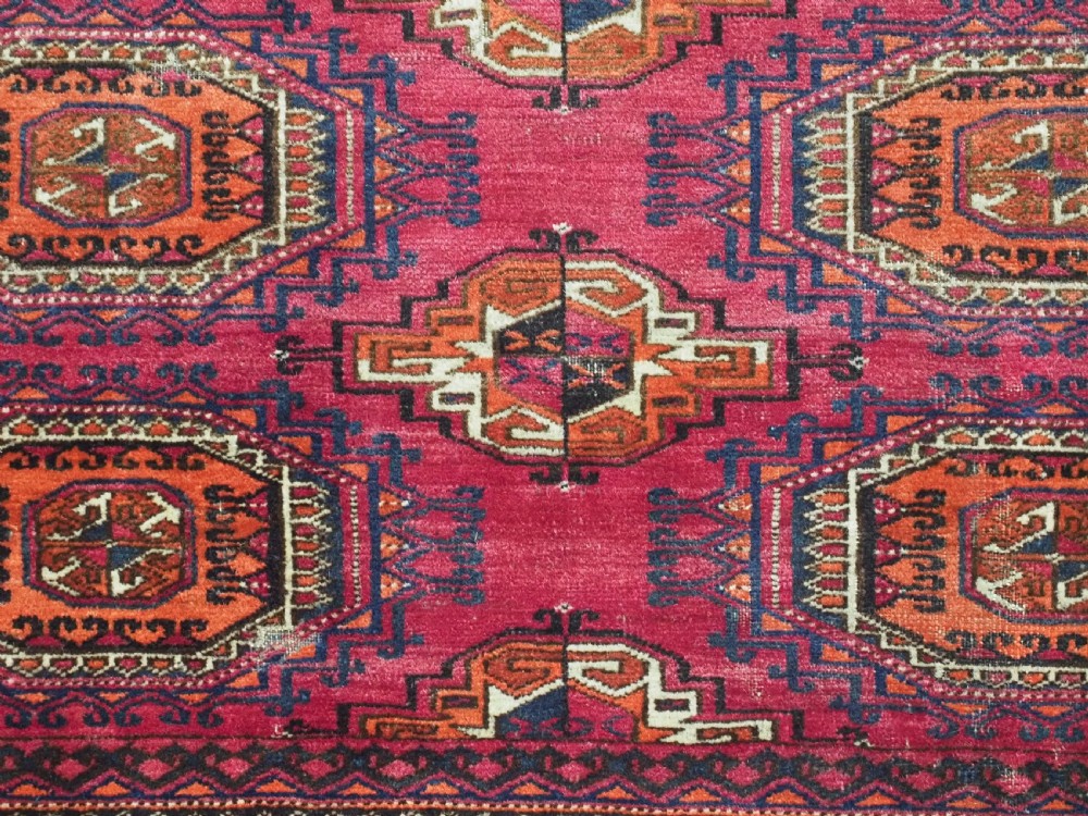 A rectangular hand-knotted crimson red Turkmen chuval featuring nine central octagonal Salor guls framed by ornate geometric borders and a decorative lower elem panel. View IX