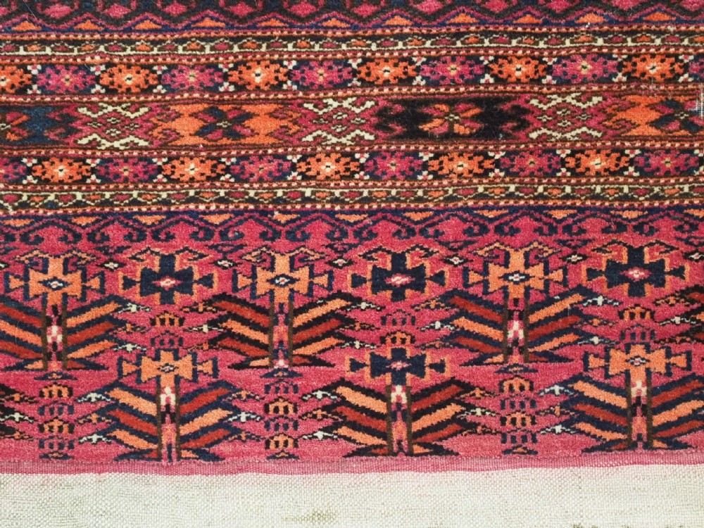 A rectangular hand-knotted crimson red Turkmen chuval featuring nine central octagonal Salor guls framed by ornate geometric borders and a decorative lower elem panel. View XI
