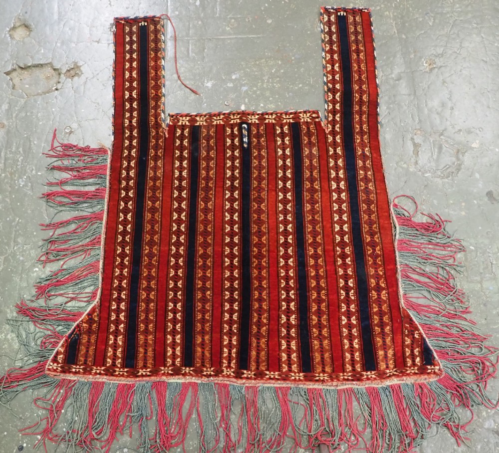 An antique Yomut Turkmen handwoven wool horse cover with vertical geometric stripes in dark blue, ivory, and terracotta red, edged with fringe trim.