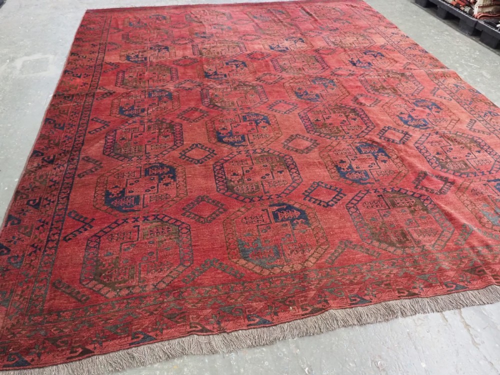 An antique hand-knotted Ersari wool carpet featuring repeating octagonal gol motifs in blue and green on a rich warm red field. View II