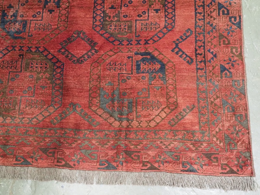 An antique hand-knotted Ersari wool carpet featuring repeating octagonal gol motifs in blue and green on a rich warm red field. View VII