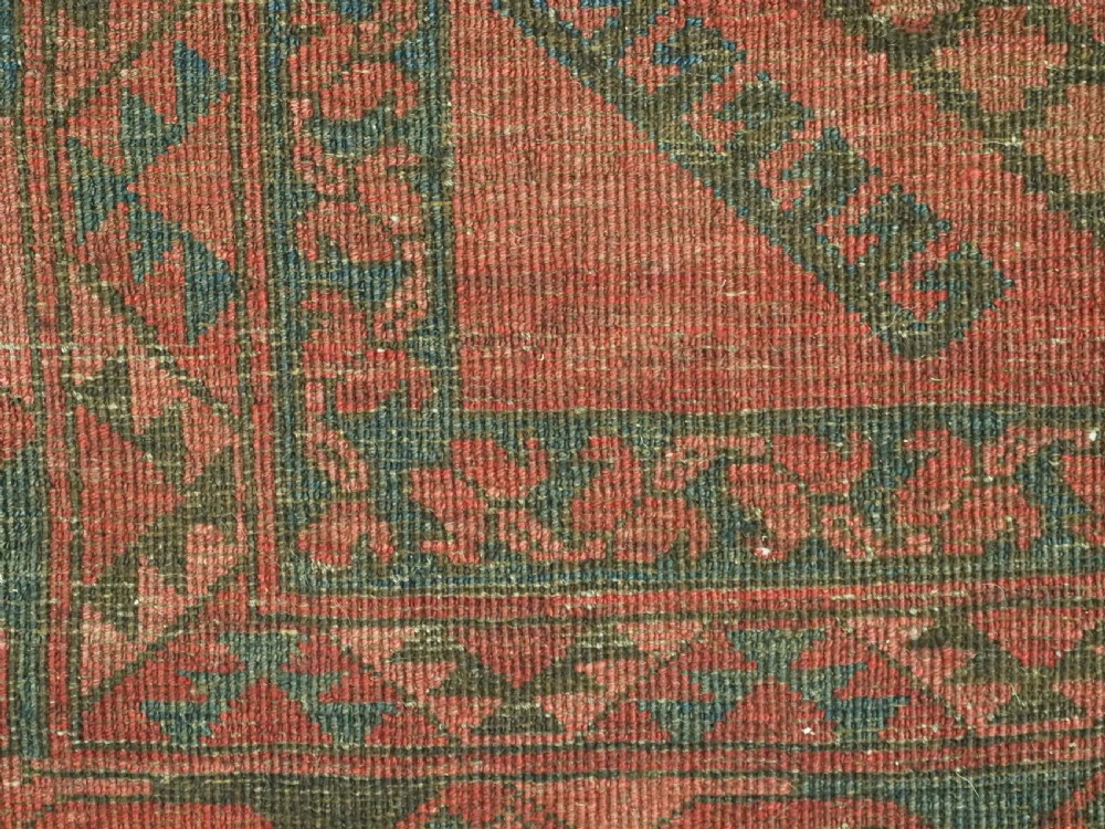 An antique hand-knotted Ersari wool carpet featuring repeating octagonal gol motifs in blue and green on a rich warm red field. View VIII
