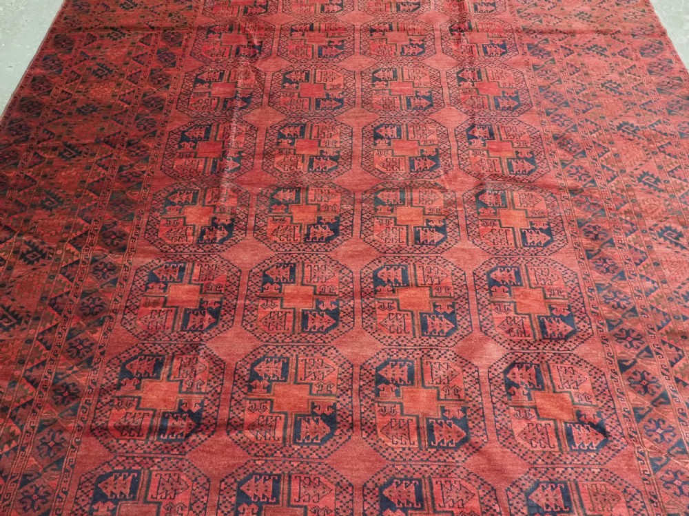 A large antique Afghan Ersari hand-knotted wool carpet featuring repeating octagonal gul motifs across a deep red field framed by geometric borders. View V