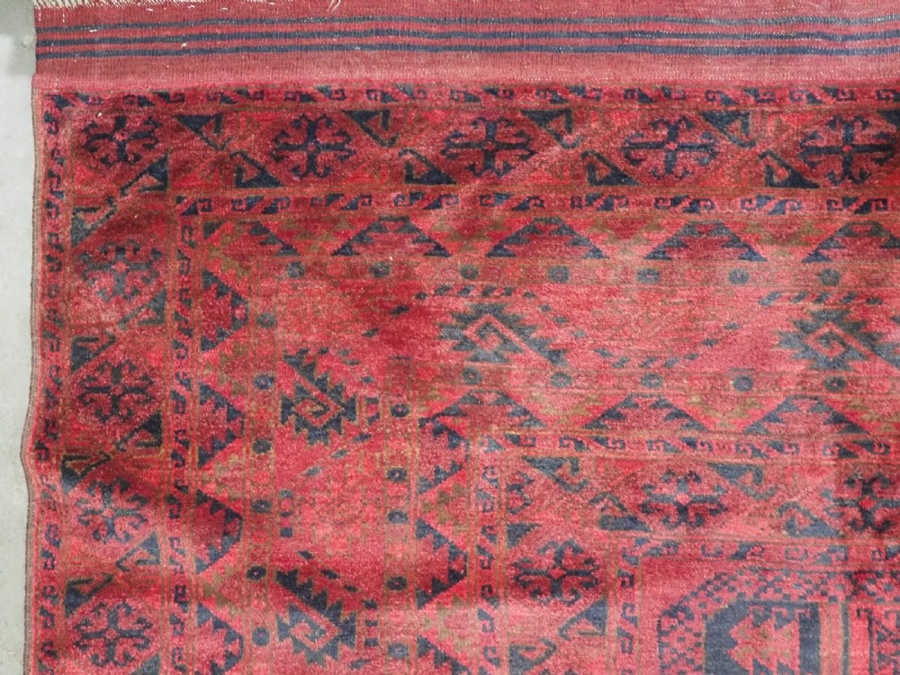 A large antique Afghan Ersari hand-knotted wool carpet featuring repeating octagonal gul motifs across a deep red field framed by geometric borders. View VII