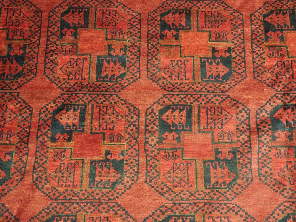 A large antique Afghan Ersari hand-knotted wool carpet featuring repeating octagonal gul motifs across a deep red field framed by geometric borders. View X