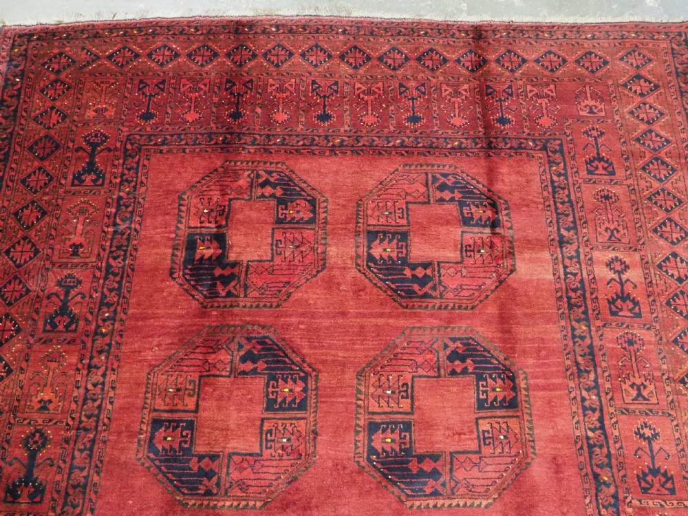 An antique hand-knotted Afghan Ersari wool carpet featuring repeating octagonal gul motifs across a deep red field framed by geometric borders. View III
