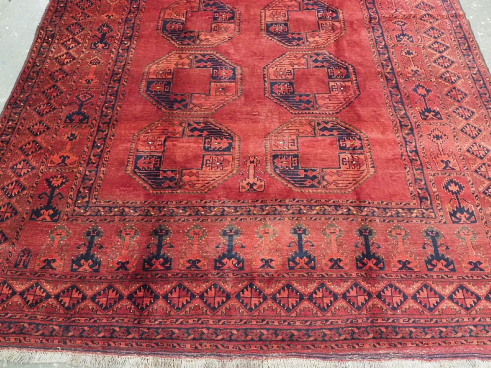 An antique hand-knotted Afghan Ersari wool carpet featuring repeating octagonal gul motifs across a deep red field framed by geometric borders. View V