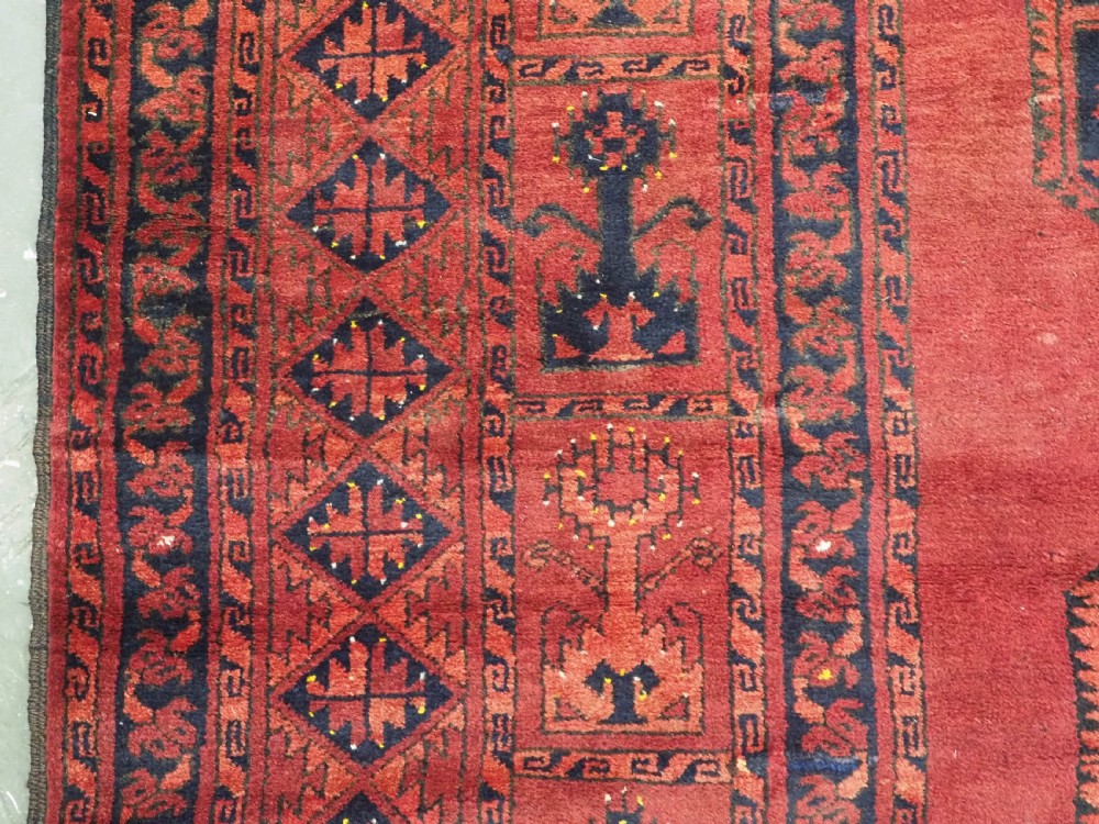 An antique hand-knotted Afghan Ersari wool carpet featuring repeating octagonal gul motifs across a deep red field framed by geometric borders. View VII
