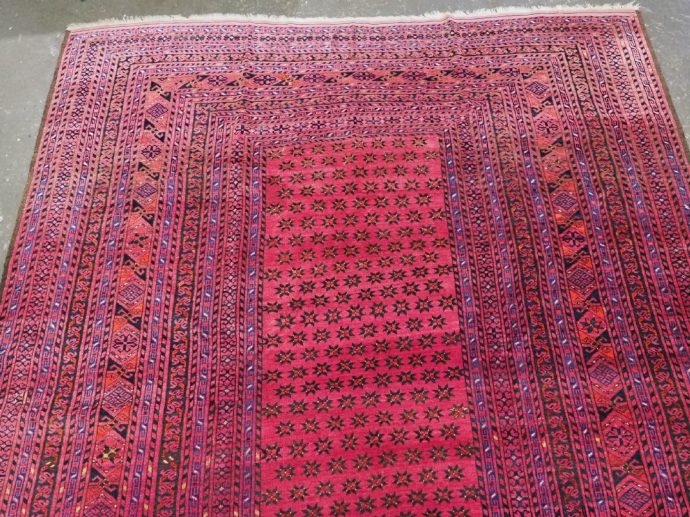 An elongated antique Afghan Ersari wool kelleh carpet featuring intricate geometric repeating motifs in shades of red, crimson, and black. View III