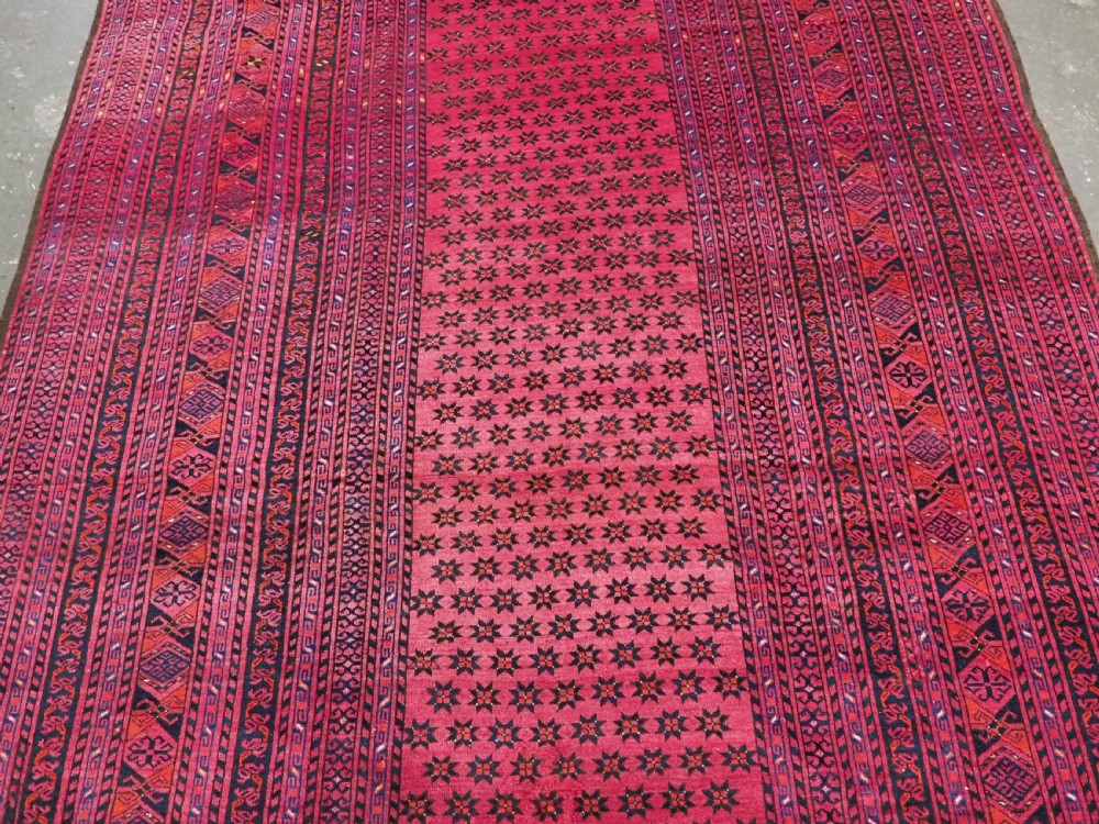 An elongated antique Afghan Ersari wool kelleh carpet featuring intricate geometric repeating motifs in shades of red, crimson, and black. View IV