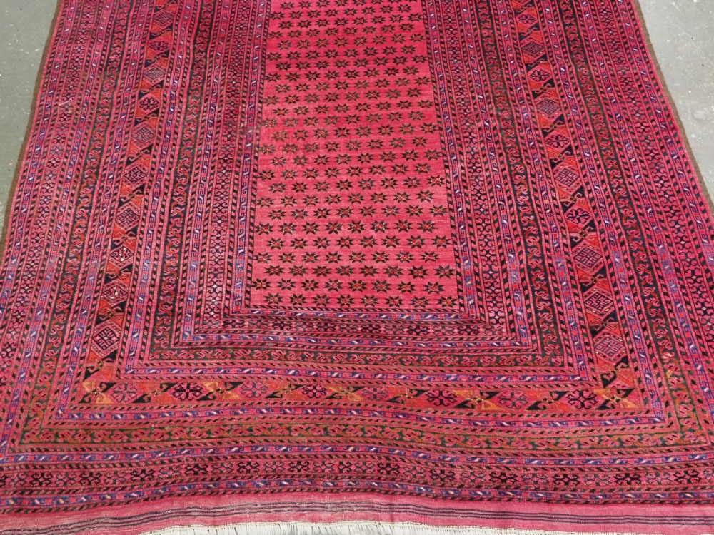 An elongated antique Afghan Ersari wool kelleh carpet featuring intricate geometric repeating motifs in shades of red, crimson, and black. View VI