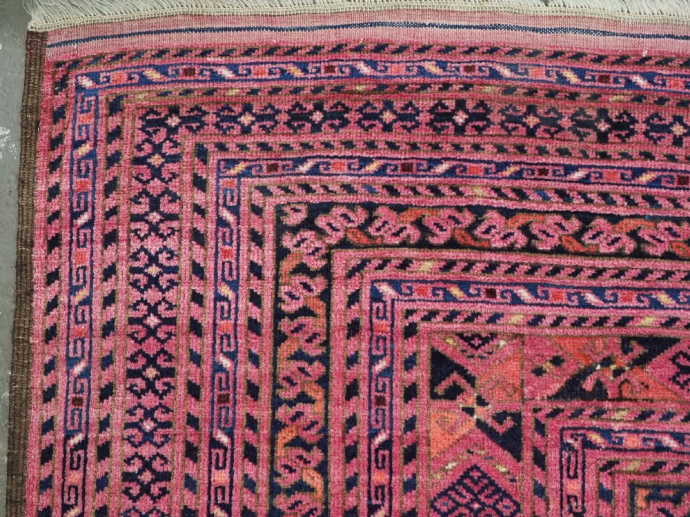 An elongated antique Afghan Ersari wool kelleh carpet featuring intricate geometric repeating motifs in shades of red, crimson, and black. View VII