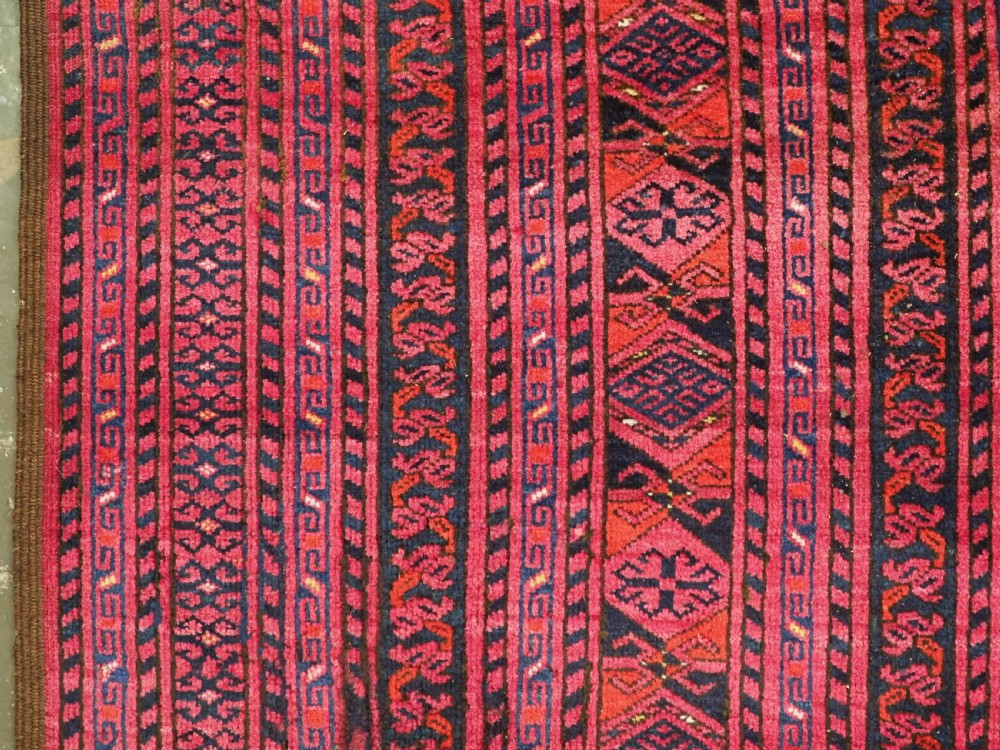 An elongated antique Afghan Ersari wool kelleh carpet featuring intricate geometric repeating motifs in shades of red, crimson, and black. View VIII