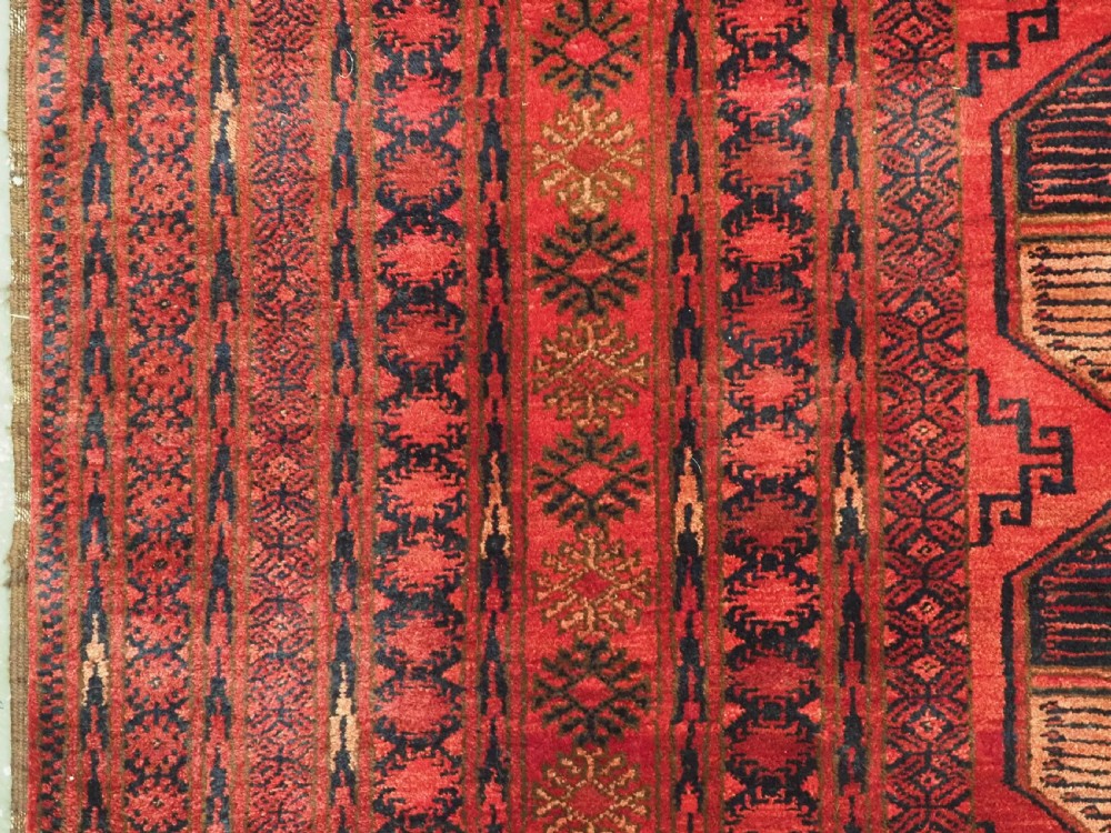 An antique Afghan Turkmen wool carpet in deep red tones featuring a repeating grid pattern of octagonal gul motifs framed by geometric borders. View VII
