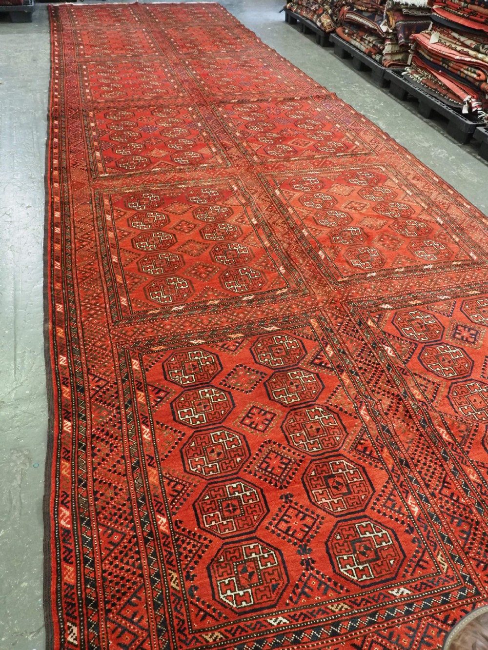 An elongated antique Turkmen Kizil Ayak wool carpet featuring multiple rectangular compartments filled with octagonal geometric guls in deep red, navy blue, and ivory tones. View II